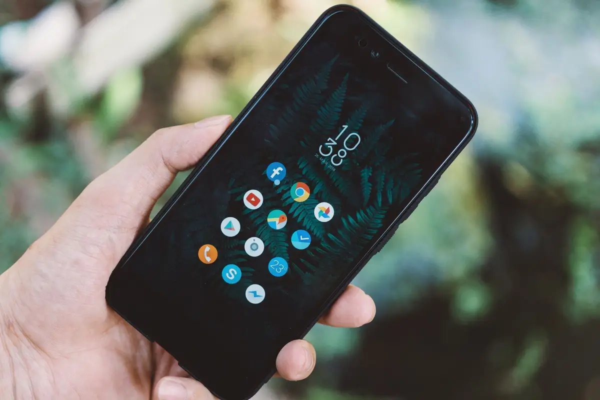 Hand holding a phone full of app icons