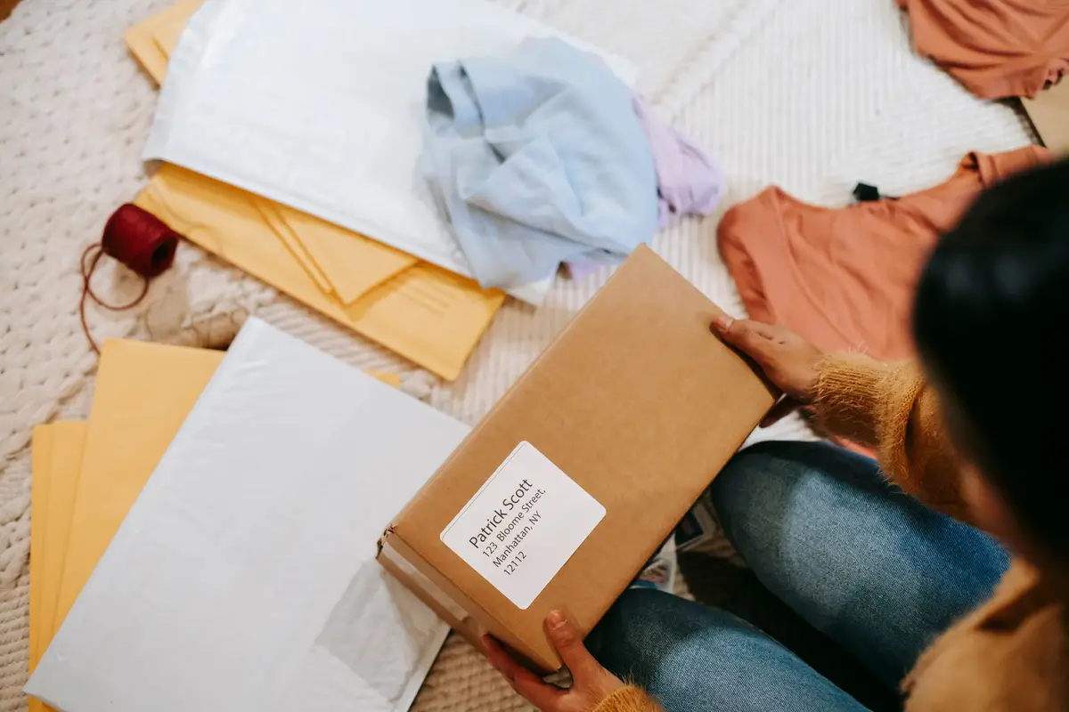 Person packing a box of clothes to post