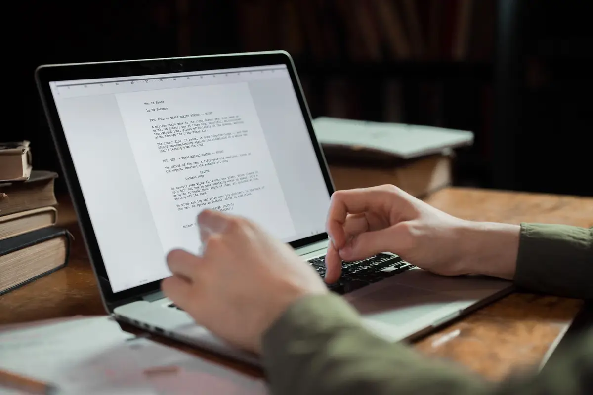 Writer typing on a laptop surrounded by books
