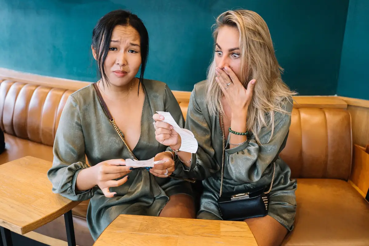 Two friends looking surprised at a restaurant bill