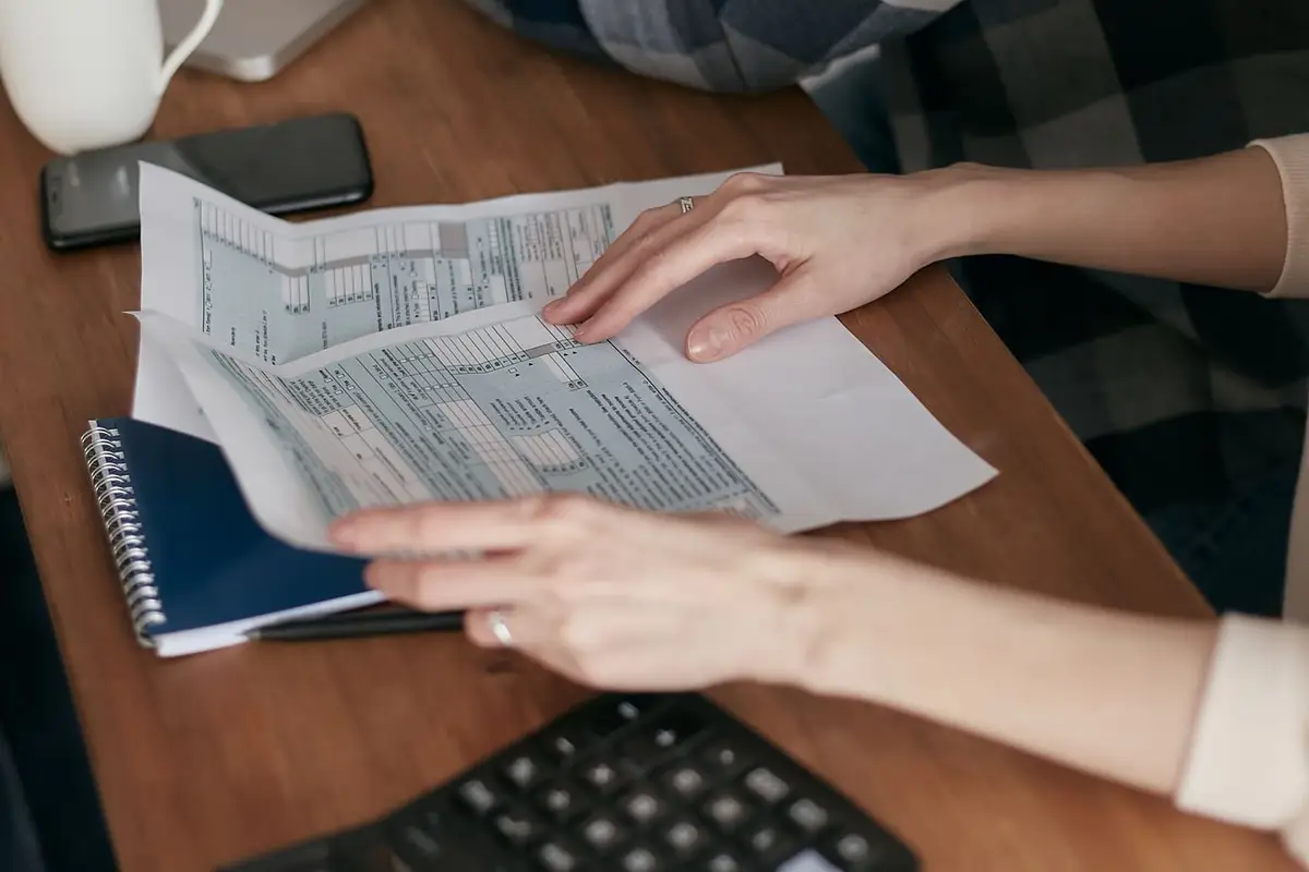 Hands organizing paperwork next to a calculator