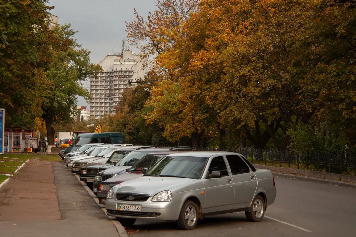 Cars parked along a tree-lined street in autumn