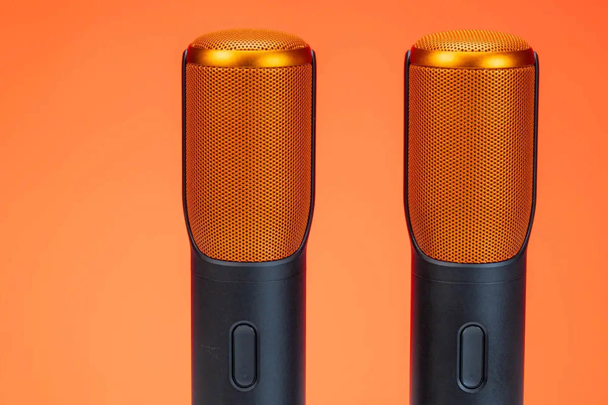 Two studio microphones against an orange background