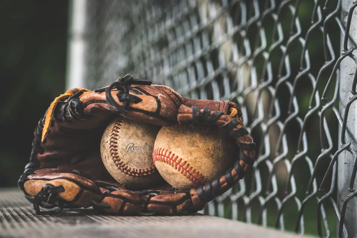 Leather baseball glove holding two vintage baseballs