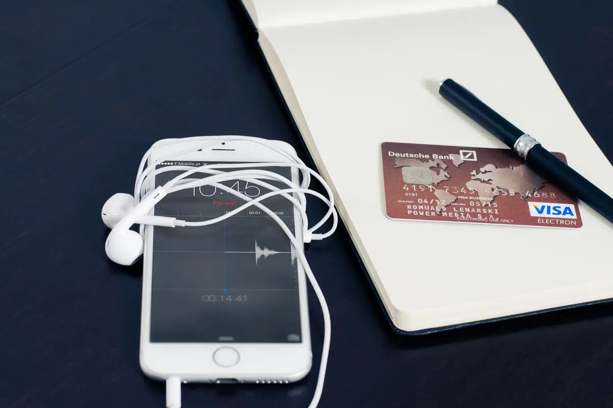 Phone, earbuds and a credit card on a desk