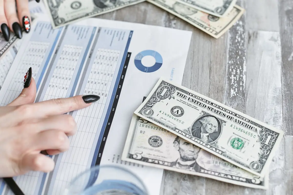 Hands reviewing a financial document with dollar bills